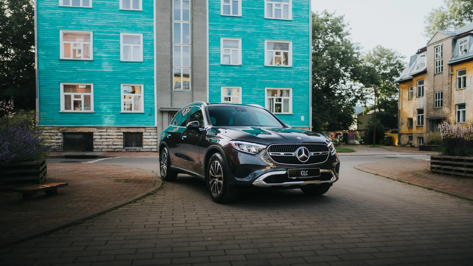 Must Mercedes-Benz GLC SUV rohelise maja taustal